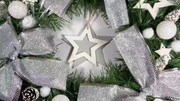 Noel çelengi ladin, gümüş yaylar, yıldızlar ve beyaz arka planda izole edilmiş Noel toplarından oluşan tatiller için ön kapıyı süslüyor. — Stok video