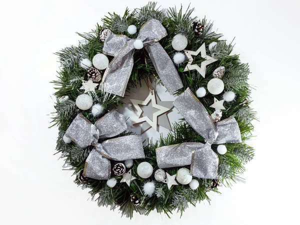 Χριστουγεννιάτικο στεφάνι στολίζει την μπροστινή πόρτα για τις γιορτές από έλατο, ασημένια τόξα, αστέρια και μπάλες Χριστουγέννων που απομονώνονται σε λευκό φόντο — Φωτογραφία Αρχείου