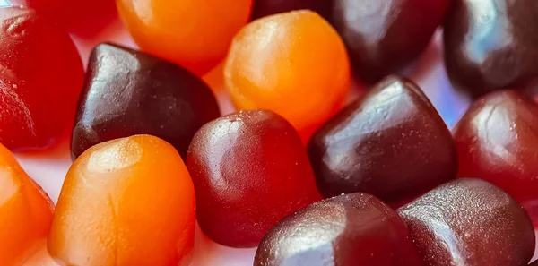 Foco seletivo.Textura close-up de gomas multivitamínicas vermelhas, laranja e roxas sobre fundo branco — Fotografia de Stock