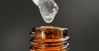 Bir damla yüz serumu olan boru ya da yüz için yağ ve güzel siyah arka planda hyaluronik asit, yakın plan.