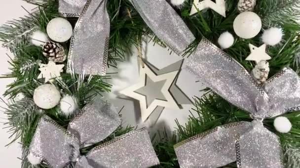 Різдвяний вінок, що прикрашає вхідні двері на свята з ялини, срібних луків, зірок та різдвяних кульок ізольовані на білому тлі — стокове відео