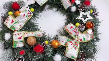 Noel çelengi ladin, gümüş yaylar, yıldızlar ve beyaz arka planda izole edilmiş Noel toplarından oluşan tatiller için ön kapıyı süslüyor.