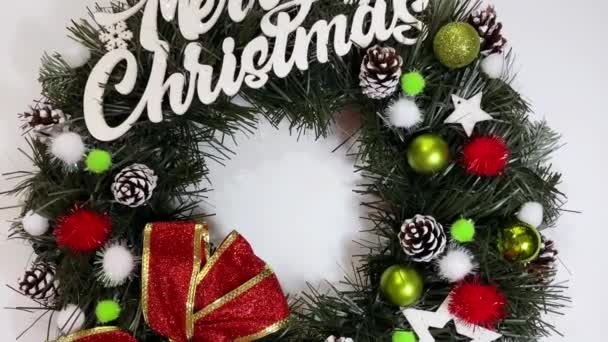 Noel çelengi ladin, gümüş yaylar, yıldızlar ve beyaz arka planda izole edilmiş Noel toplarından oluşan tatiller için ön kapıyı süslüyor. — Stok video