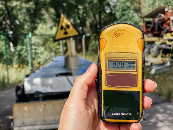 In the hand is a dosimeter that measures the level of radiation against the background of the city in which a catastrophe once occurred and a large amount of radioactive substances were released into