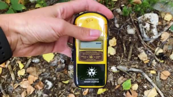 У руці - дозиметр, який вимірює рівень радіації на тлі міста Прип'ять, в якому колись сталася катастрофа, і велика кількість радіоактивних речовин. — стокове відео