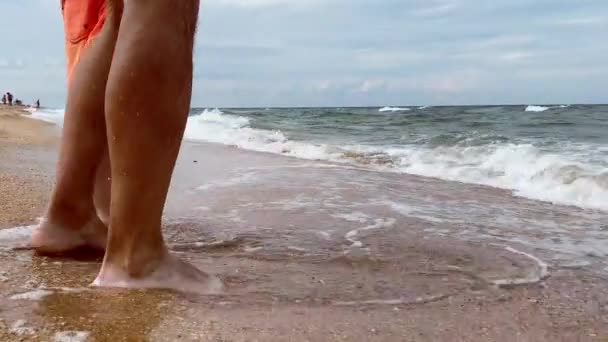 Close-up dad and son are standing near the seashore and slapping their feet on the sea water. Vacation and tourism concept — Stock Video