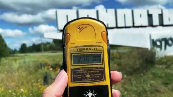 Στο χέρι είναι ένα δοσίμετρο που μετρά το επίπεδο της ακτινοβολίας στο φόντο της πόλης Pripyat στην οποία μια καταστροφή συνέβη κάποτε και μια μεγάλη ποσότητα ραδιενεργών ουσιών ήταν — Αρχείο Βίντεο