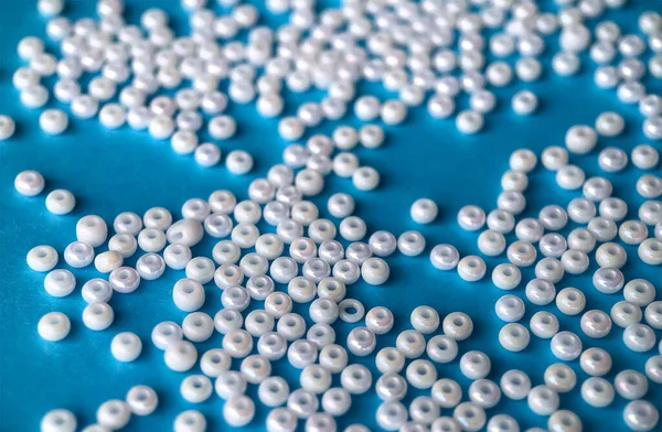 Focus sélectif, perles de perles blanches pour la broderie sur fond bleu. Fabrication de bijoux à partir de perles, broderie, mosaïque et tricot — Photo