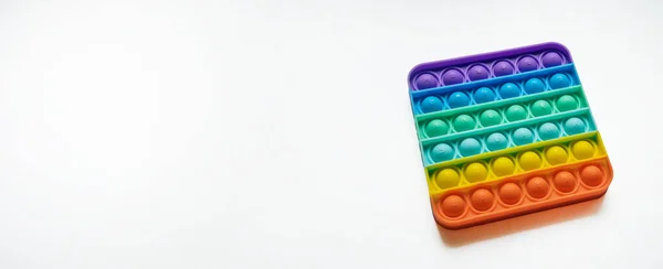 Çocuklar için gökkuşağı anti-stresli parmak itme oyuncağı beyaz arka planda izole edilmiş.