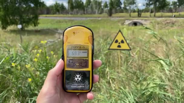 Na mão é um dosímetro que mede o nível de radiação contra o fundo da cidade Pripyat em que uma catástrofe ocorreu uma vez e uma grande quantidade de substâncias radioativas foram — Vídeo de Stock