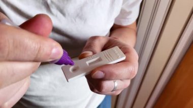 Beyaz adam koronavirüs için antijen testi yapıyor. Sonuçları belirlemek için ayırıcının teste damladığı aşama