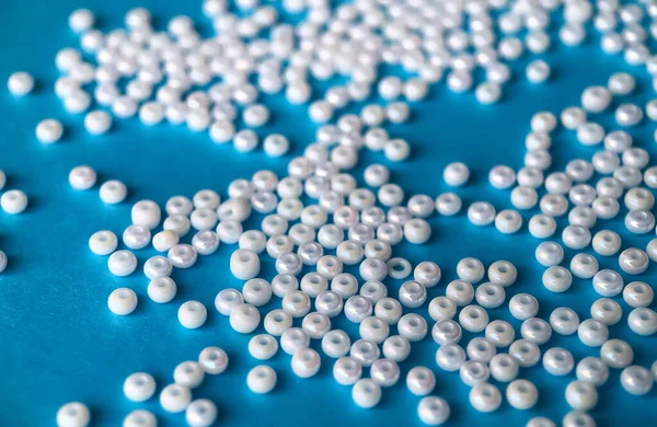 Focus sélectif, perles de perles blanches pour la broderie sur fond bleu. Fabrication de bijoux à partir de perles, broderie, mosaïque et tricot — Photo