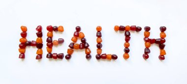 Bir grup kırmızı, turuncu ve mor multivitamin sakızı sağlık sözcüğü şeklinde dizilmiştir.