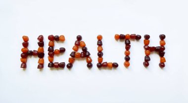 Bir grup kırmızı, turuncu ve mor multivitamin sakızı sağlık sözcüğü şeklinde dizilmiştir.