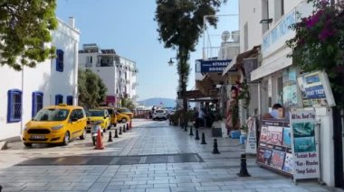Türkiye 'de bir tatil köyü boyunca palmiye ağaçları, dükkanlar, plaj şemsiyeleri arasında mavi gökyüzüne karşı yürüyün