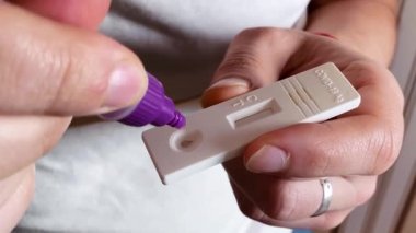 Beyaz adam koronavirüs için antijen testi yapıyor. Sonuçları belirlemek için ayırıcının teste damladığı aşama