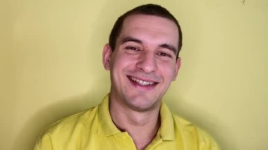 Beyaz bir adamın portresi gülümseyen ve sarı arka planda parmağını kaldıran
