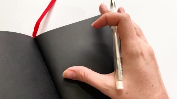 Demostración en primer plano de un cuaderno con papel negro para inscripciones en tinta blanca — Vídeos de Stock