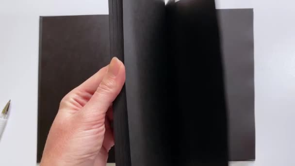 Beyaz mürekkepli yazıtlar için siyah kağıtlı bir defterin yakın plan gösterimi — Stok video
