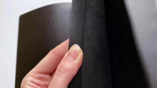 Demonstrasi close-up dari notebook dengan kertas hitam untuk inskripsi dengan tinta putih — Stok Video