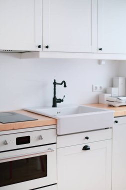 Lavabosu, sandviç makinesi, ocağı, yemek masası ve penceresi olan beyaz tonda bir mutfağın içi.