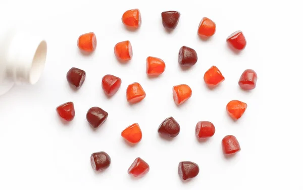 Gruppo di gomme multivitaminiche rosse, arancioni e viola con la bottiglia isolata su sfondo bianco. — Foto Stock