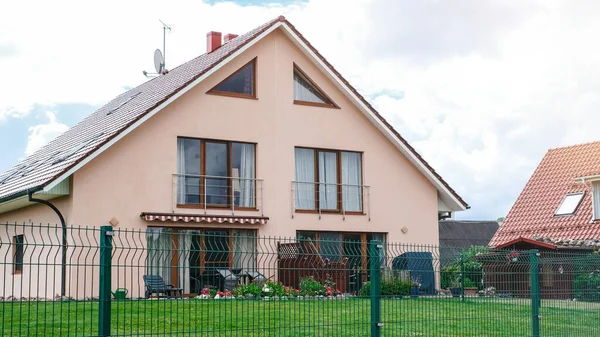 İki katlı, üçgen çatılı ve mavi gökyüzüne karşı evin yakınındaki özel bir ev...