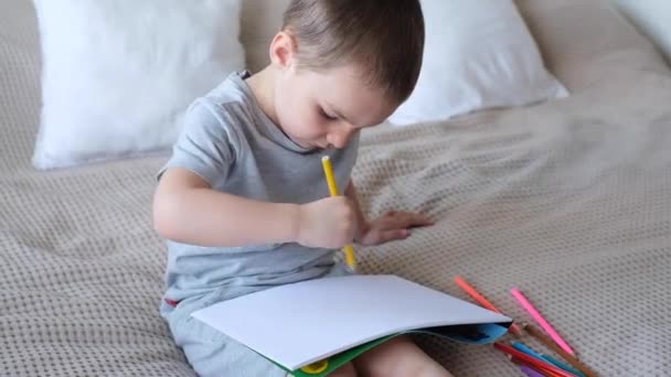 Small Caucasian Boy Gray Shirt Shorts Bed Draws Colored Pencils — Stok video