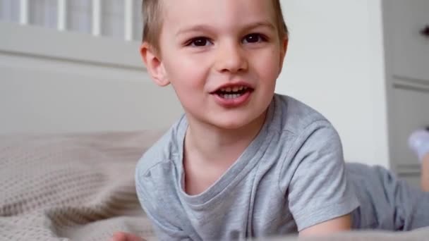 Gri Tişörtlü Küçük Mutlu Beyaz Bir Çocuğu Yakından Çek Yatağa — Stok video
