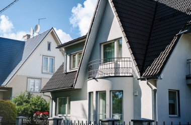 İki katlı, üçgen çatılı ve mavi gökyüzüne karşı evin yakınındaki özel bir ev..