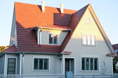 İki katlı, üçgen çatılı ve mavi gökyüzüne karşı evin yakınındaki özel bir ev..