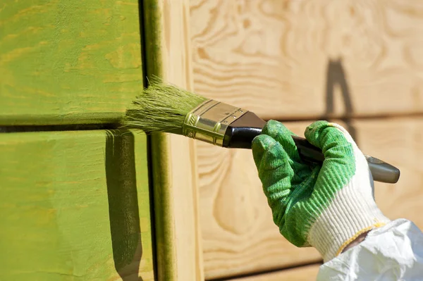 Main avec un pinceau peinture mur en bois — Photo