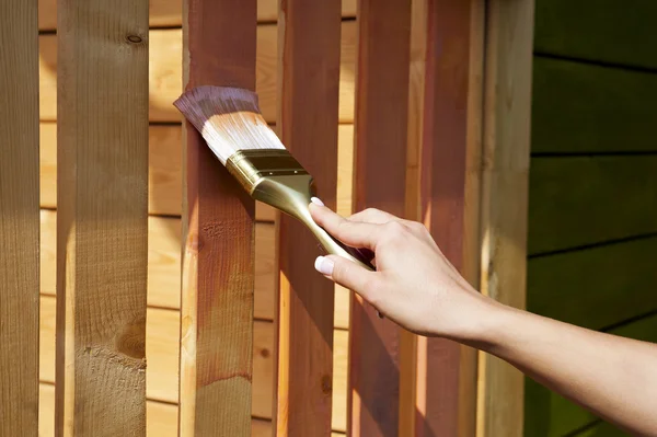 Ženská ruka s Malování štětcem malby dřevěné terasy — Stock fotografie