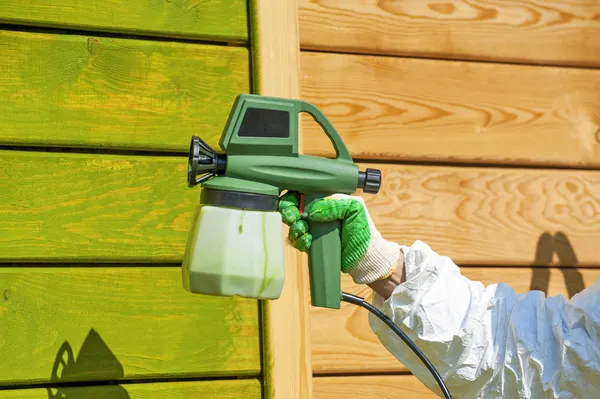 Hand painting wooden wall with spray gun — Stock Photo, Image