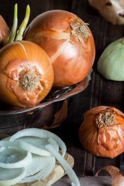 İçinde biraz soğan olan metal bir kap. Dilimlenmiş soğanlı bir tahta var. dikey stüdyo resmi