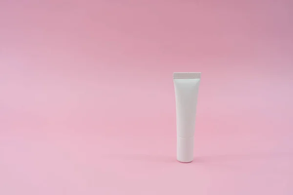 White plastic tube on pink background. Cosmetic bottles for beauty or medicine products