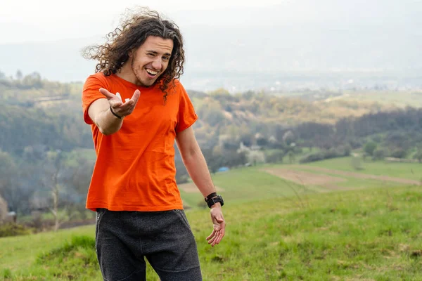 Young man laughs and fools on top of the mountain