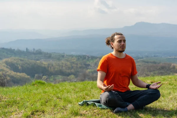 Young man meditating yoga on the rock peak. Relax and calm