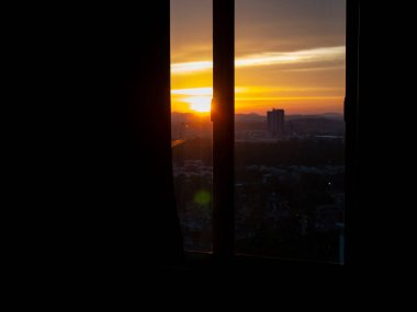 Pencereden parlak turuncu gün batımı görünümü