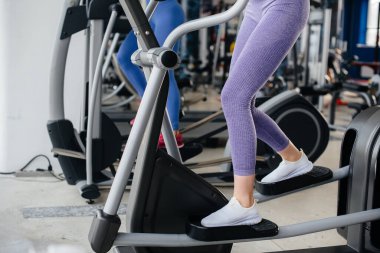 Salgın sırasında maske takan iki güzel kız spor salonunda egzersiz yapıyor. Halka açık yerlerde sosyal mesafeler.