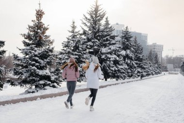 Güneşli bir kış gününde parkta koşan iki genç atletik kız. Sağlıklı bir yaşam tarzı.