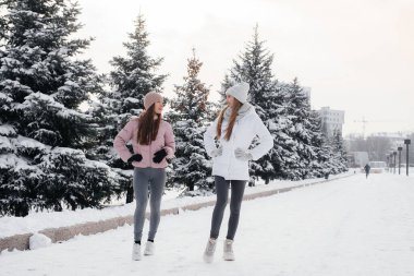 Güneşli bir kış gününde yürüyen ve spor yapan iki genç atletik kız. Sağlıklı bir yaşam tarzı.