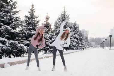 Güneşli bir kış gününde koşmadan önce iki genç atletik kız ısınma egzersizi yapıyor. Sağlıklı bir yaşam tarzı.