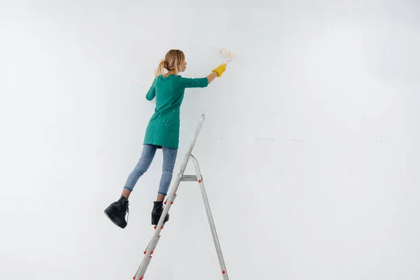 Una Joven Sobre Una Escalera Pinta Una Pared Blanca Con — Foto de Stock