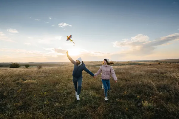 幸せなカップルは凧を飛ばし 新鮮な空気の中で一緒に時間を過ごす 幸せな関係と家族の休暇 — ストック写真