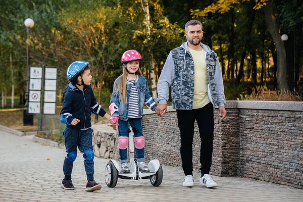 Батько Допомагає Вчить Своїх Маленьких Дітей Їздити Сегвей Парку Під — стокове фото