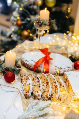 Geleneksel Noel arkaplanda mumlarla süslenmiş kurutulmuş meyve ve fındıklardan yapılmış pudra şekeri serpiştirilmiş. Geleneksel Noel keki.