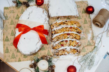 Geleneksel Noel arkaplanda mumlarla süslenmiş kurutulmuş meyve ve fındıklardan yapılmış pudra şekeri serpiştirilmiş. Geleneksel Noel keki.