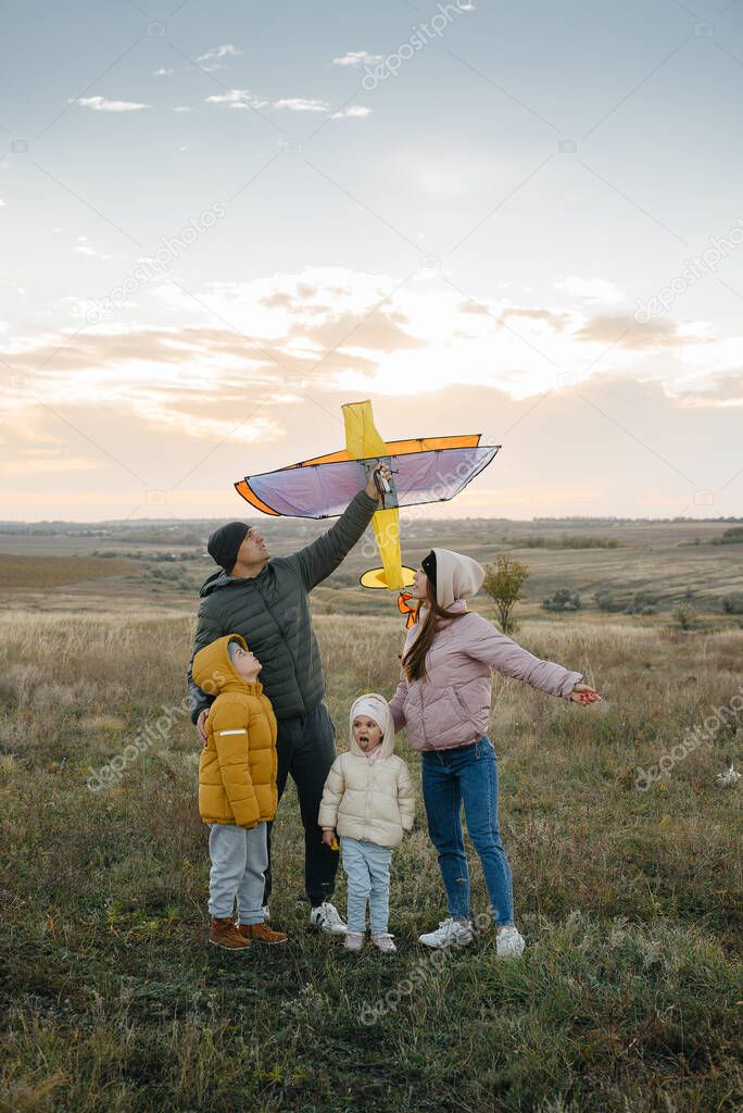 A happy family with kids launches a kite and spends time together in the fresh air. Happy childhood and family holidays.