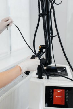 Kozmetik uzmanının eli modern bir lazeri yakın plan güzellik salonunda ayarlıyor. Lazer darbeleri deriyi temizler. Donanım kozmetolojisi. Fototermoliz süreci, deriyi ısıtır..